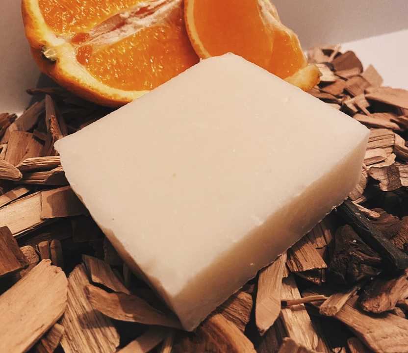 Photo of beef tallow soap from O’Naturelle surrounded by cedarwood chips and an orange